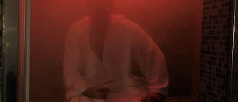 A person sitting in a dimly lit room with a red light source above.