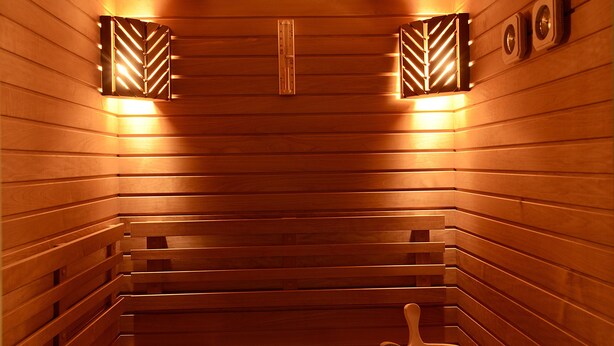 A wooden sauna with benches, a wooden bucket, and wall-mounted light fixtures. - Forum Palace Hotel (Cassino)