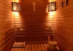 A wooden sauna with benches, a wooden bucket, and wall-mounted light fixtures. - Forum Palace Hotel (Cassino)