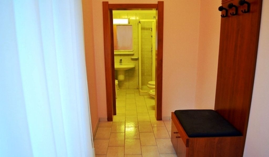 A narrow hallway leading to a bathroom with a sink and toilet.