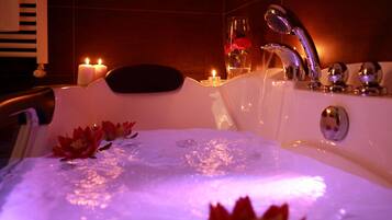 A bathtub with a lotus flower decoration, candles, and a glass vase with flowers.