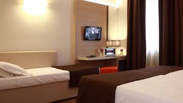A hotel room with two beds, a desk with a computer, a TV, and a lamp.