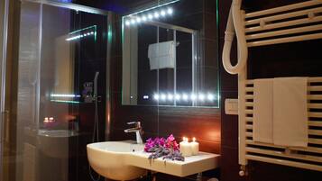 Ein Badezimmer mit Duschkabine aus Glas, einem Waschbecken mit Spiegel und einem Handtuchhalter.