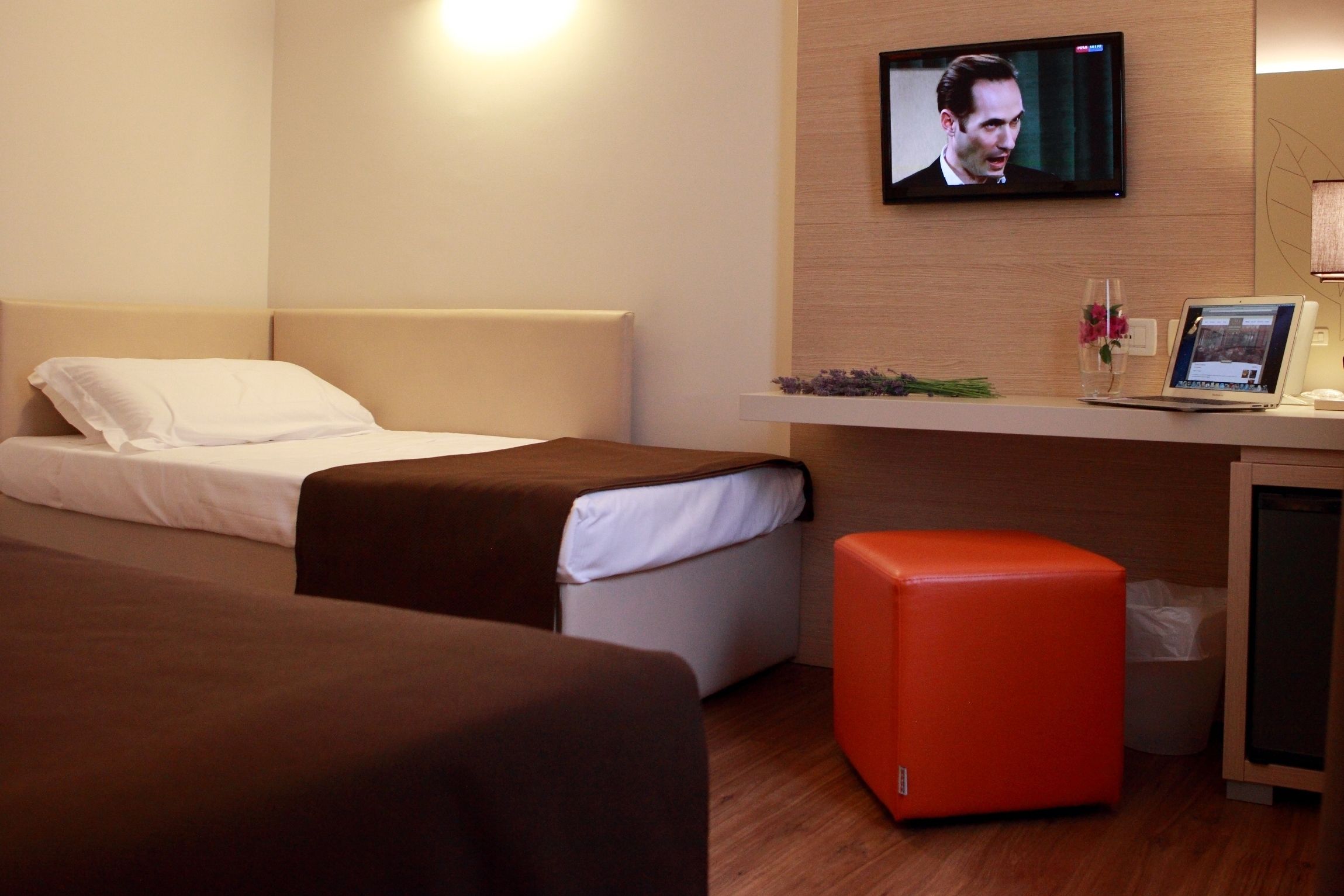 Ett hotellrum med två sängar, ett skrivbord med en bärbar dator, en tv och en papperskorg.