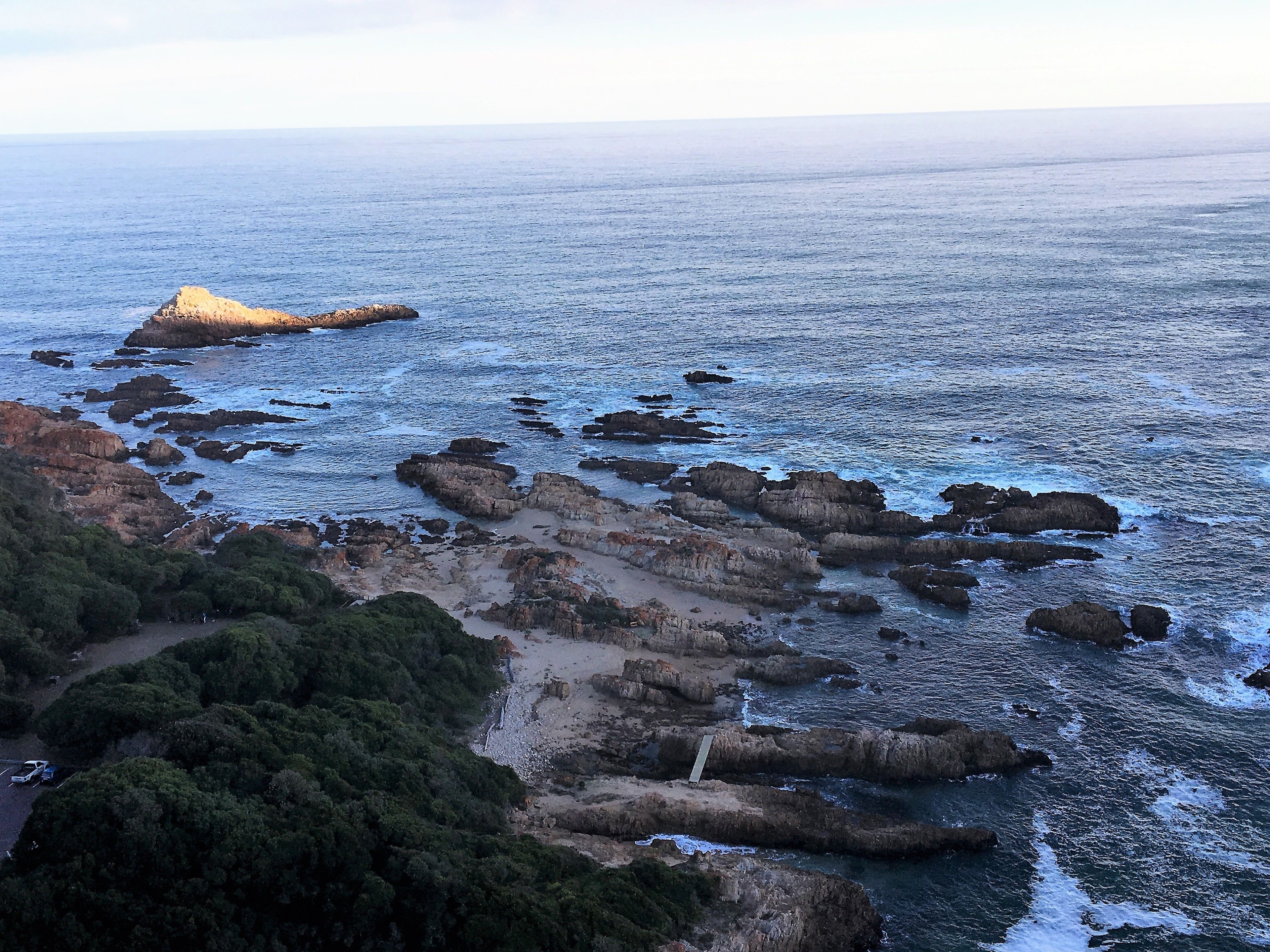 A coastal landscape with rocky formations and a clear view of the sea.