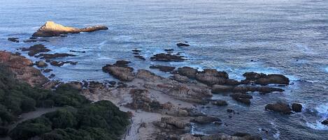 A coastal landscape with rocky formations and a clear view of the sea.