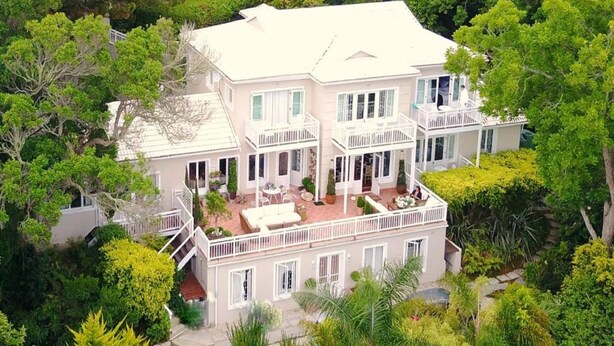 A large, multi-story house with a white exterior, multiple balconies, and a well-maintained garden. - Roseroc Boutique Guest House (Knysna)