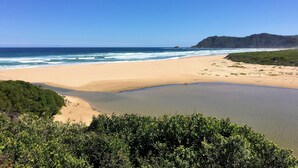 A beach with clear skies, calm waters, and a distant mountain. - Roseroc Boutique Guest House (Knysna)