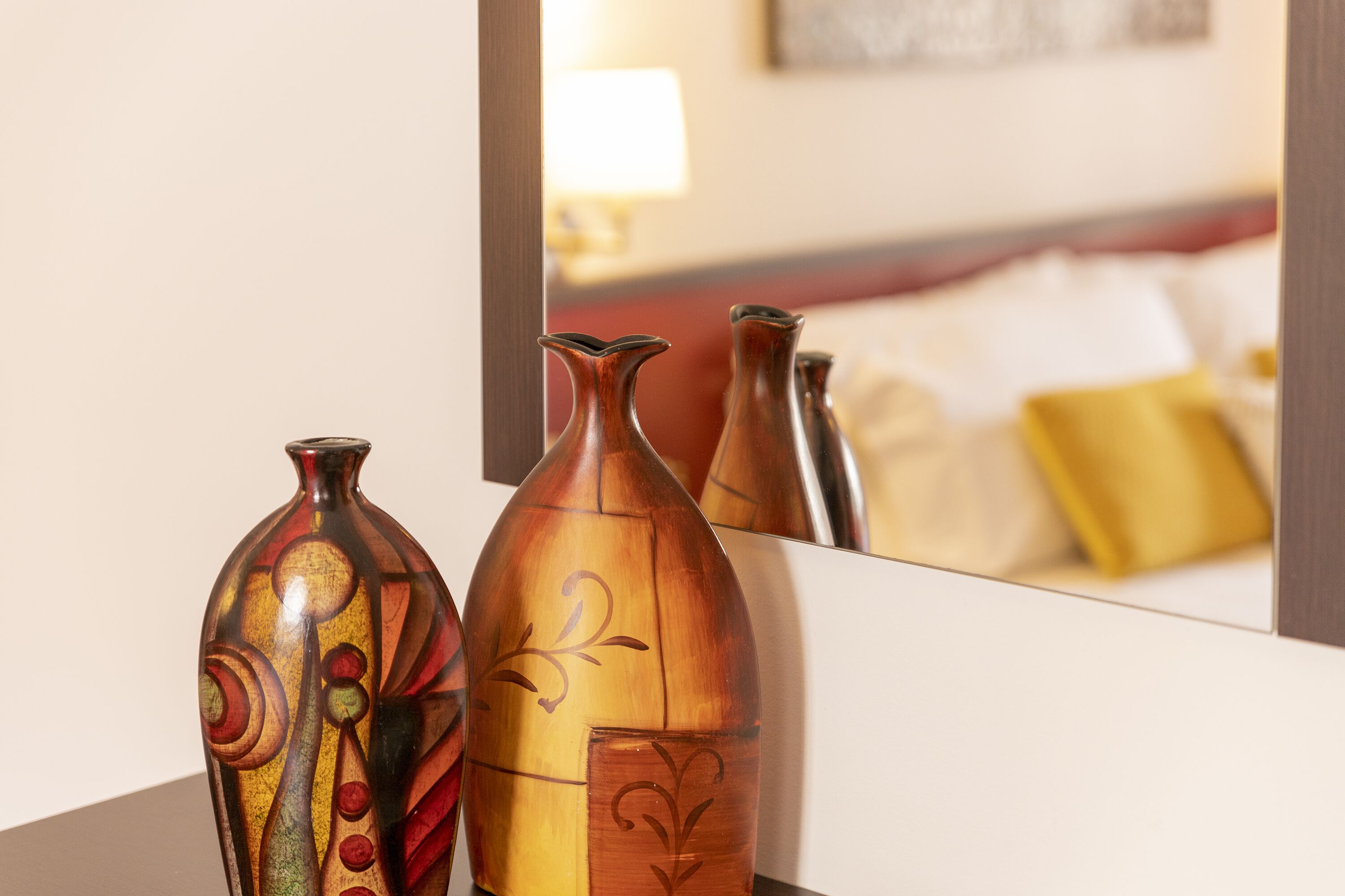 Drie decoratieve vazen op een tafel, met een weerspiegeling van een kamer op de achtergrond.