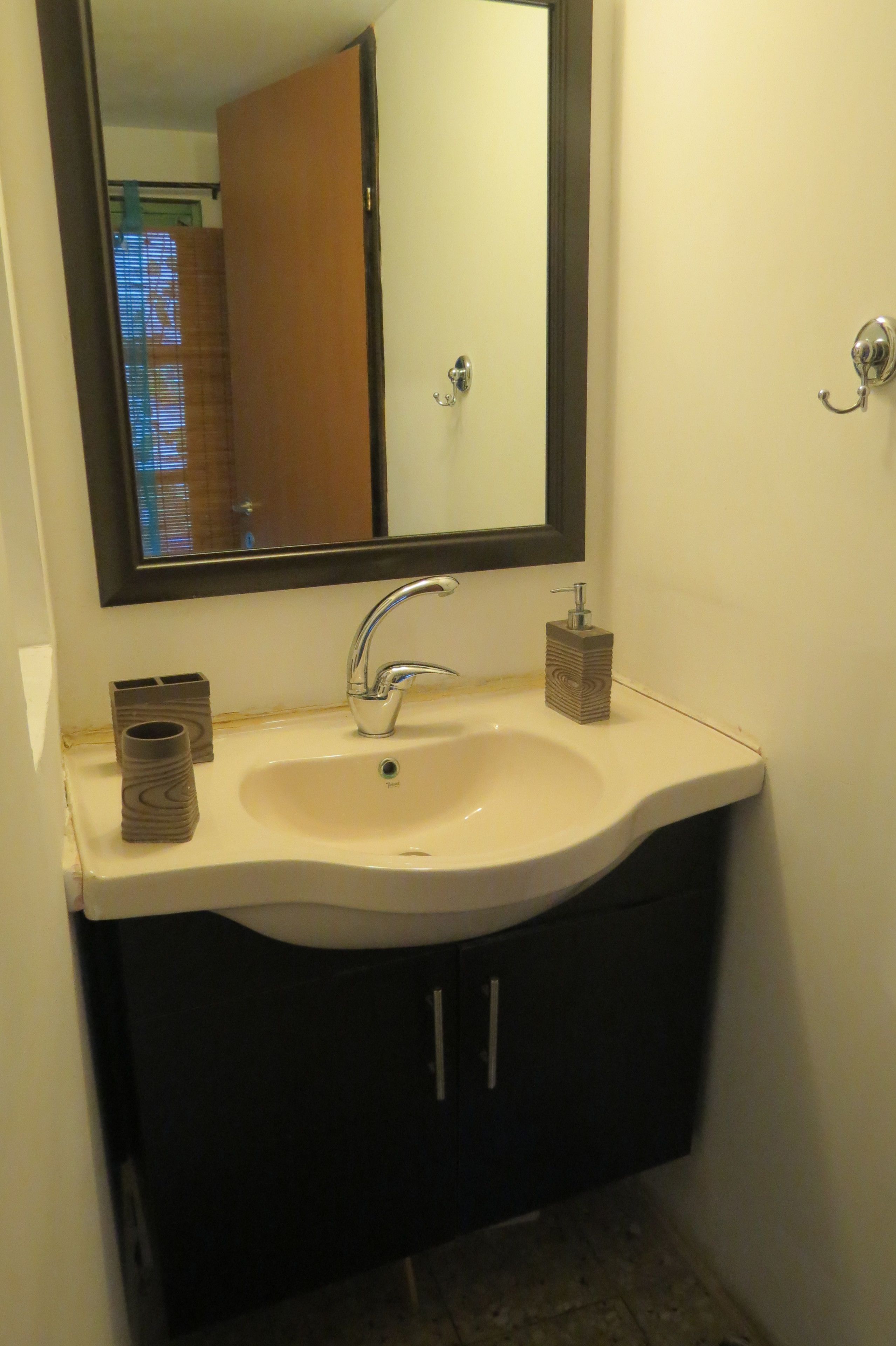 Un baño con un lavabo blanco, un espejo y un mueble oscuro.