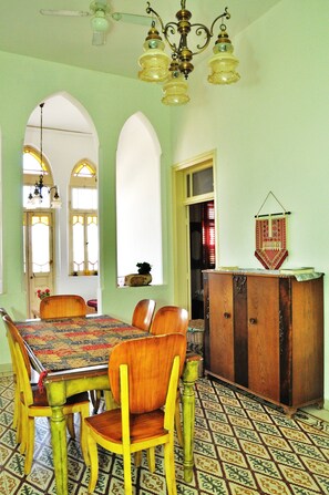 A dining area with a wooden table and chairs, a patterned tablecloth, and a chandelier. - Al-Mutran Guest House (Nazareth)