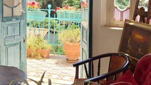 A room with a view of a cityscape, a wooden chair, a table, and potted plants. - Al-Mutran Guest House (Nazareth)