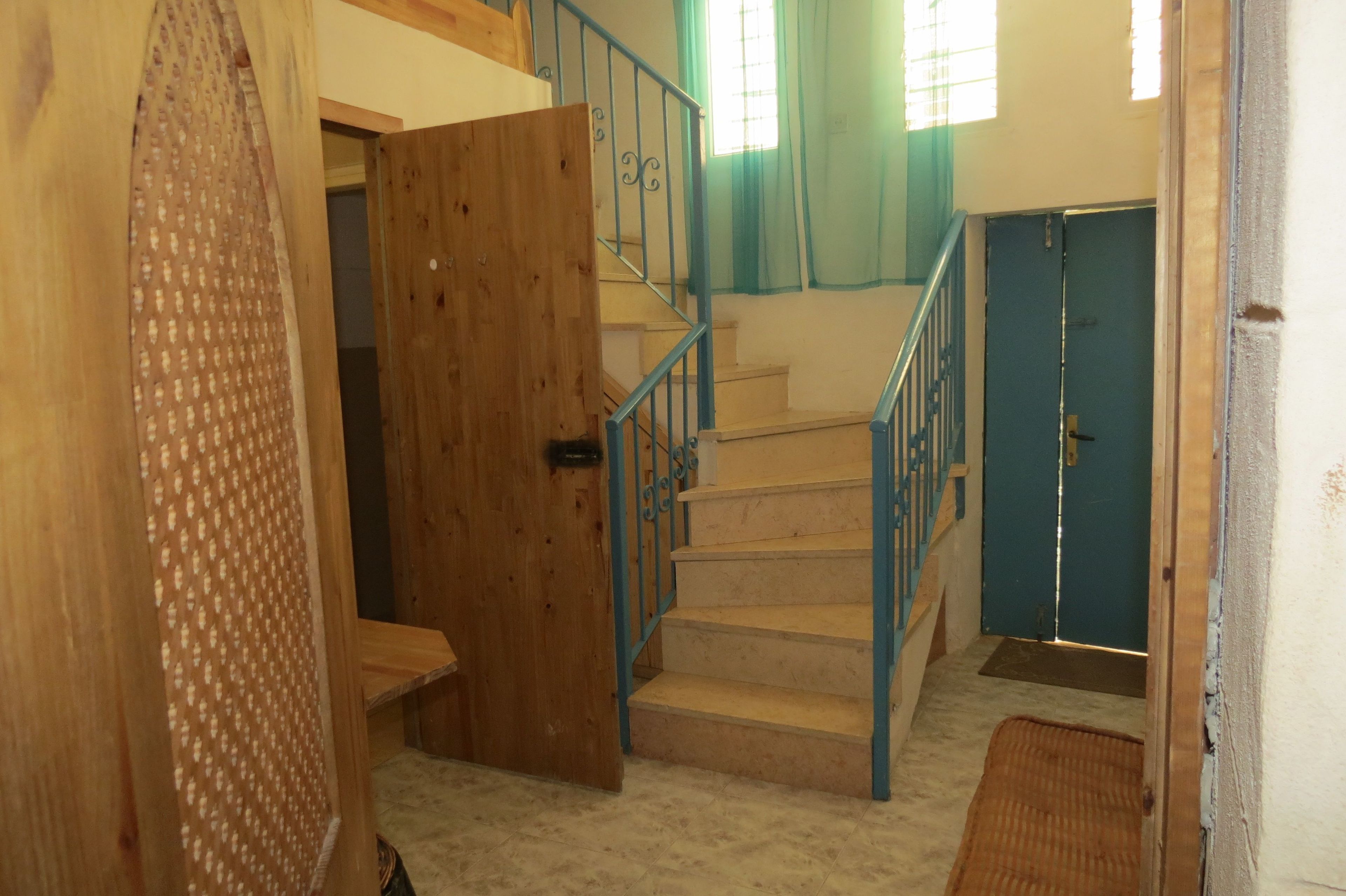 A staircase with blue railings leading to a door.