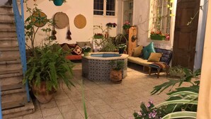 A cozy indoor garden with a variety of potted plants, a small fountain, and a comfortable seating area with cushions. - Al-Mutran Guest House (Nazareth)