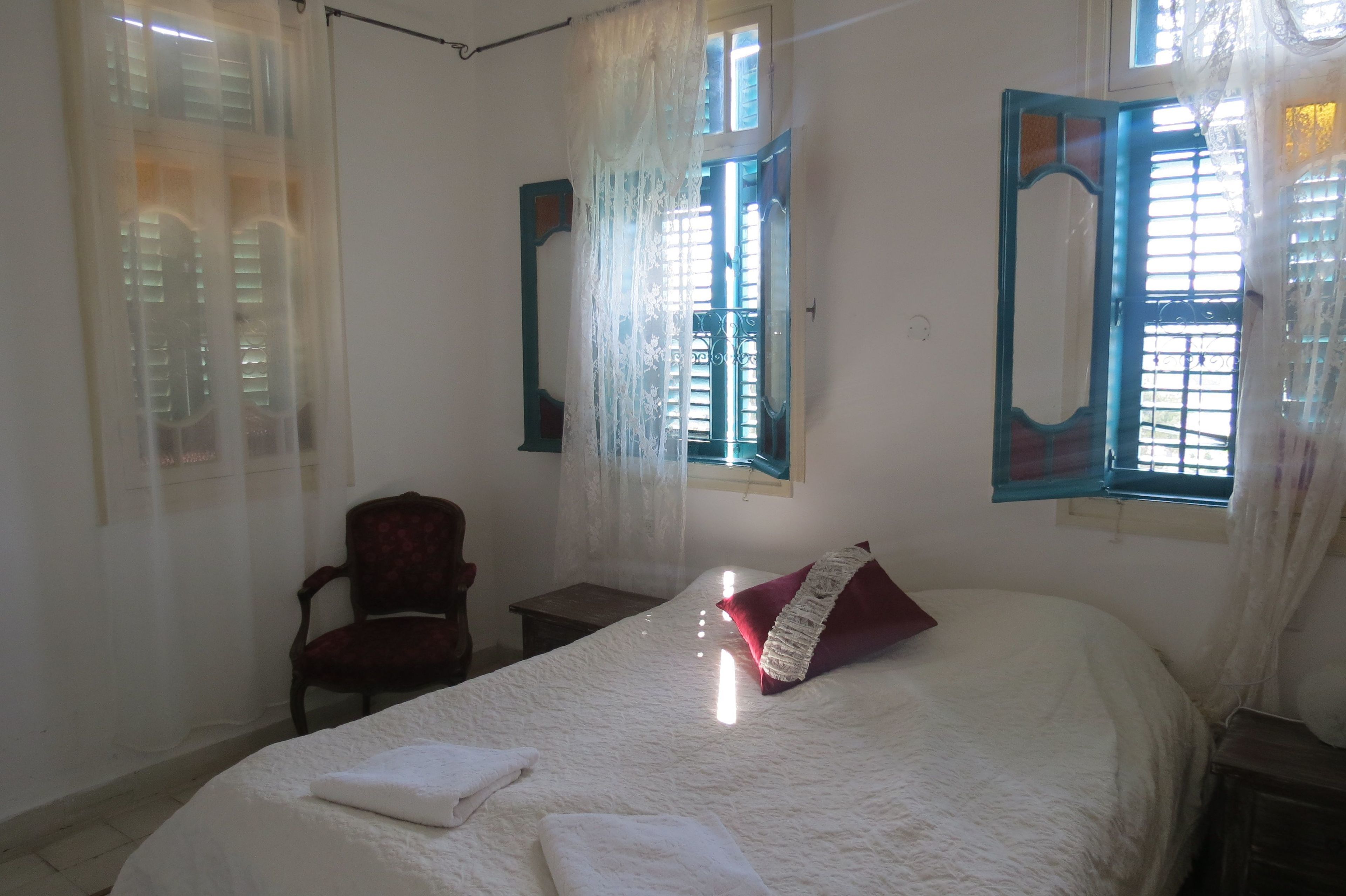 A bedroom with a bed, a chair, and a window with curtains.