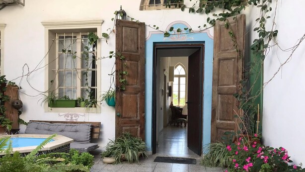 A traditional house with a wooden door, a small pool, and various potted plants. - Al-Mutran Guest House (Nazareth)