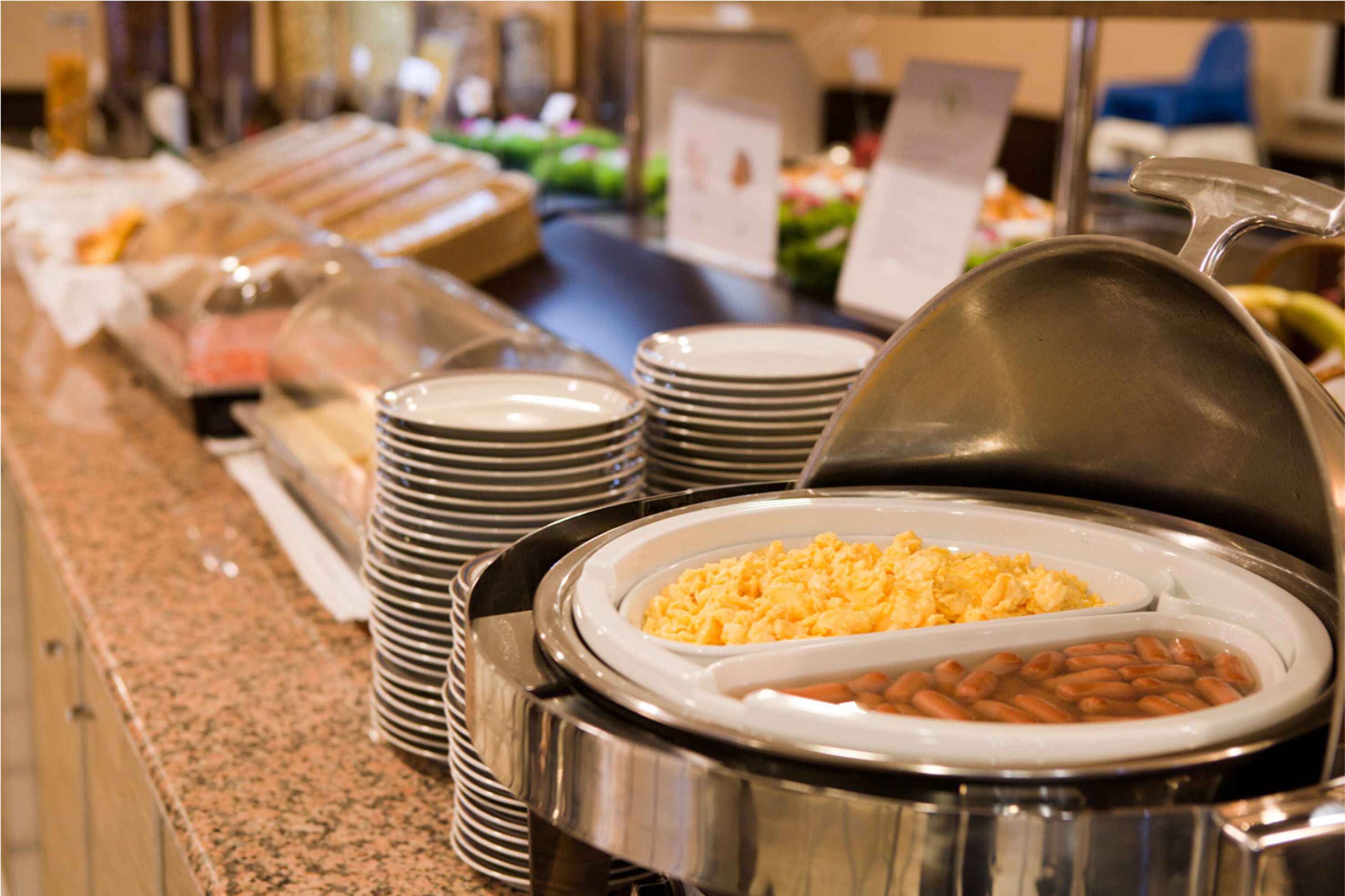 Un buffet con diversi cibi, tra cui una pirotta di uova strapazzate e un contenitore di fagioli.