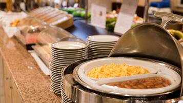 Un buffet con diversi cibi, tra cui una pirotta di uova strapazzate e un contenitore di fagioli.