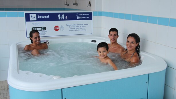 A family in a hot tub with a sign indicating a 20-minute limit and a 4-pass rule. - Hotel Feira Pedra Bela (Santa Maria da Feira)