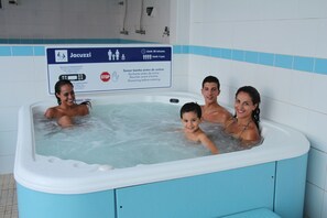 Una familia en un jacuzzi, con un cartel que indica un límite de 20 minutos y una regla de cuatro usos.