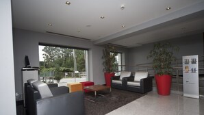 A modern lobby with seating areas, a coffee table, and potted plants. - Hotel Feira Pedra Bela (Santa Maria da Feira)
