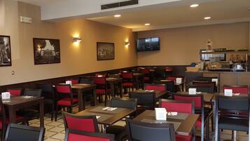Un restaurante con mesas, sillas, un televisor en la pared y una zona de bufé.