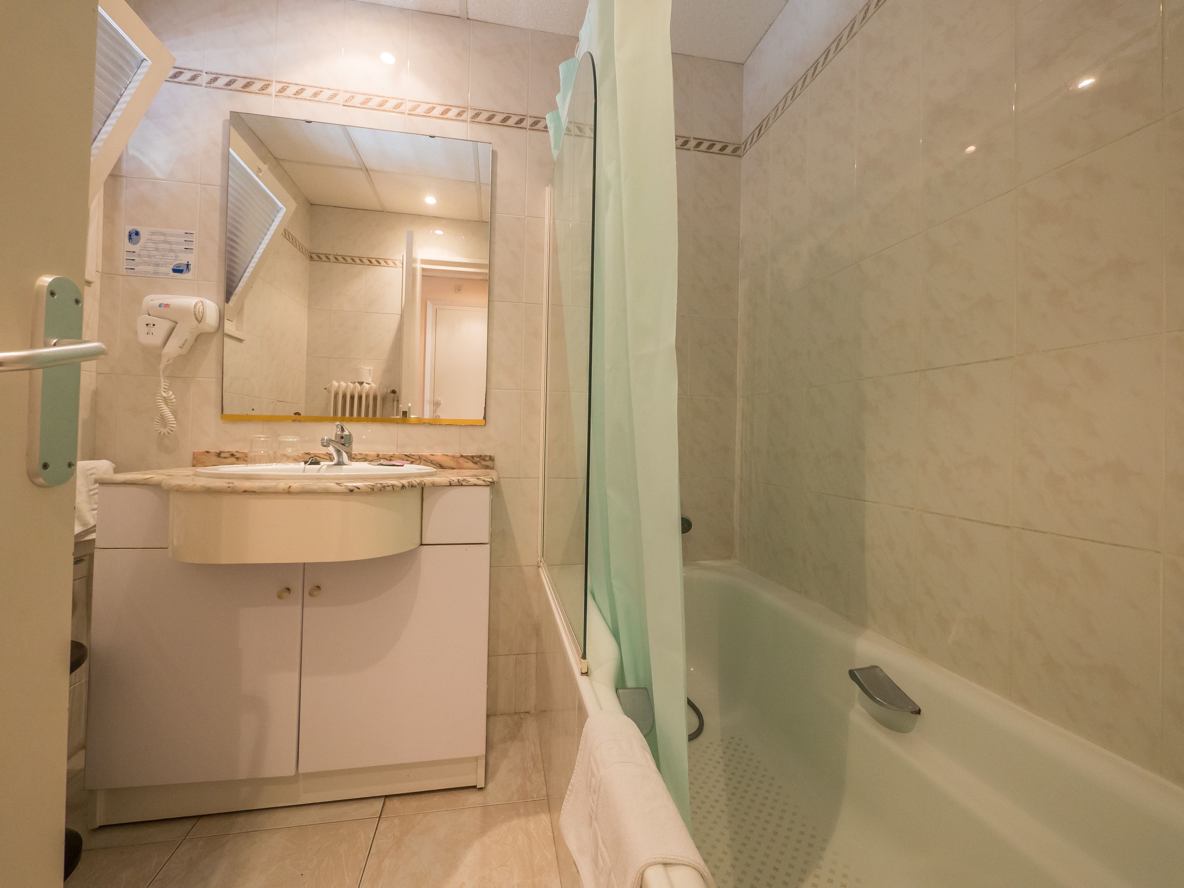 Ein Badezimmer mit Waschbecken, Spiegel, Haartrockner und Duschbereich.