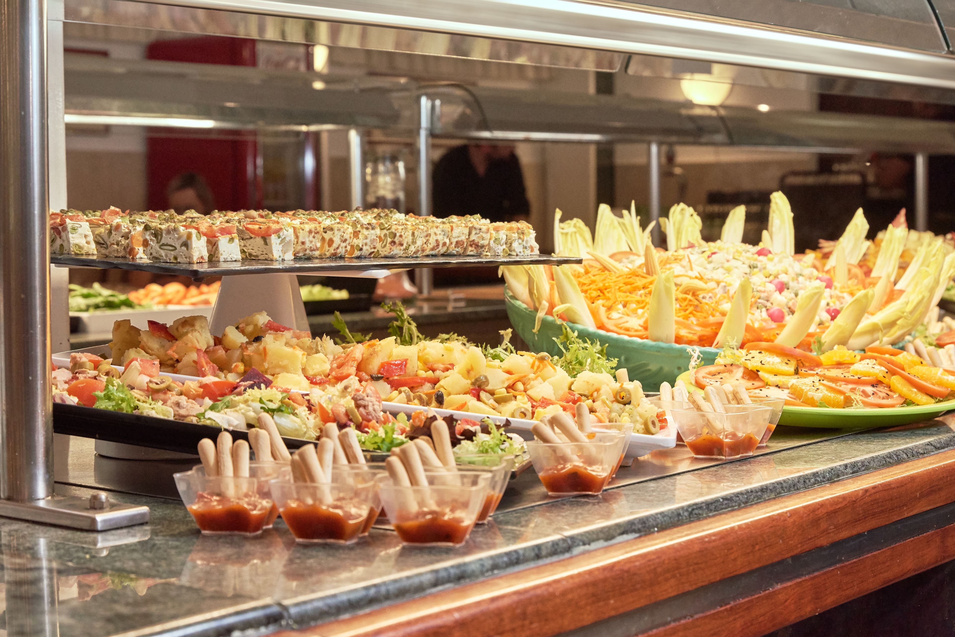 Un buffet proposant une variété de plats, notamment des salades, des pâtes et des légumes.