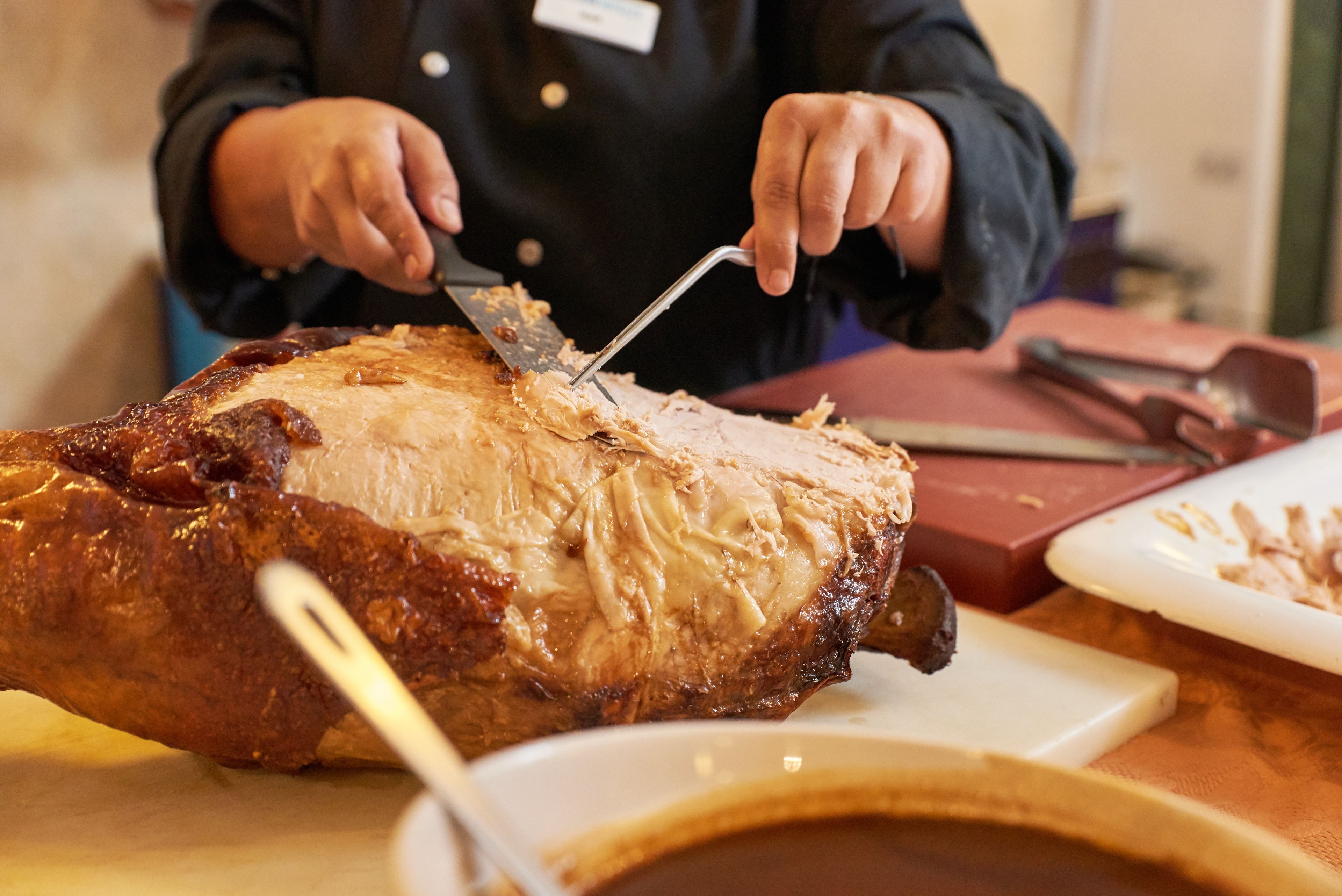 A person carving a large roasted meat on a table.