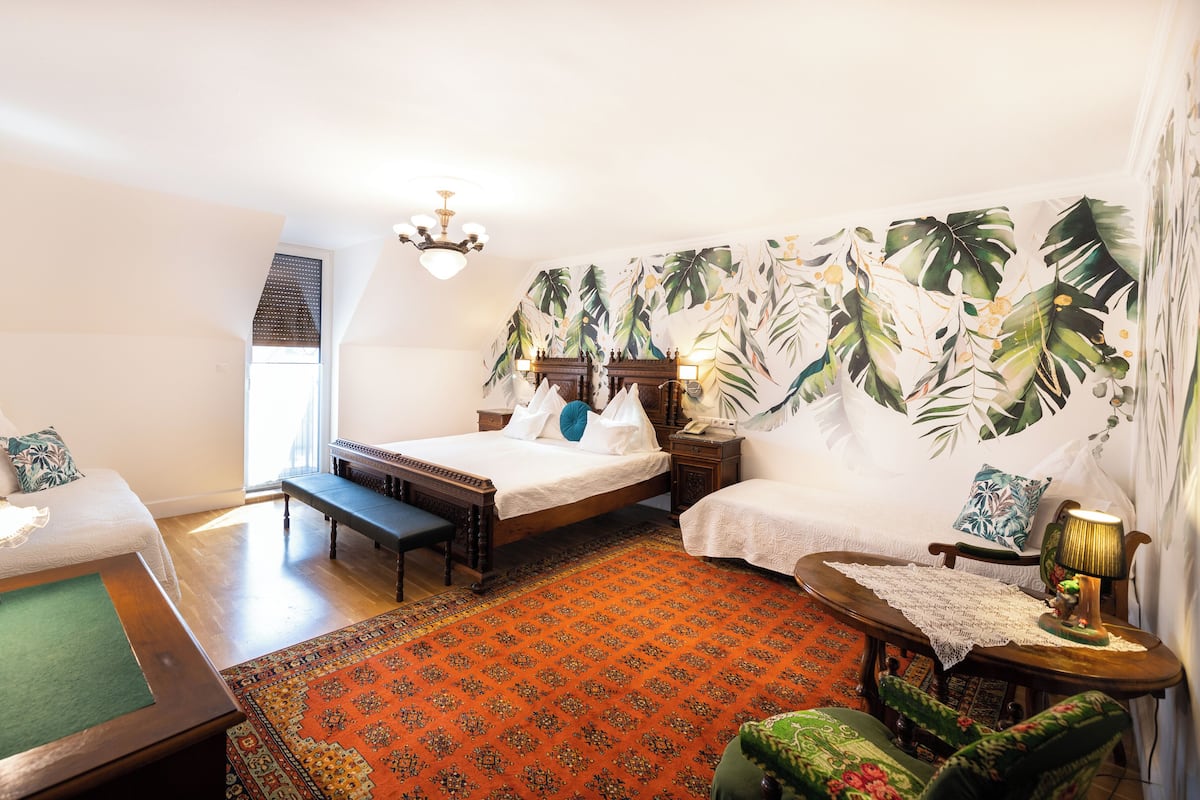 Ein Hotelzimmer mit zwei Betten, einer Bank, einem kleinen Tisch und einem Stuhl.