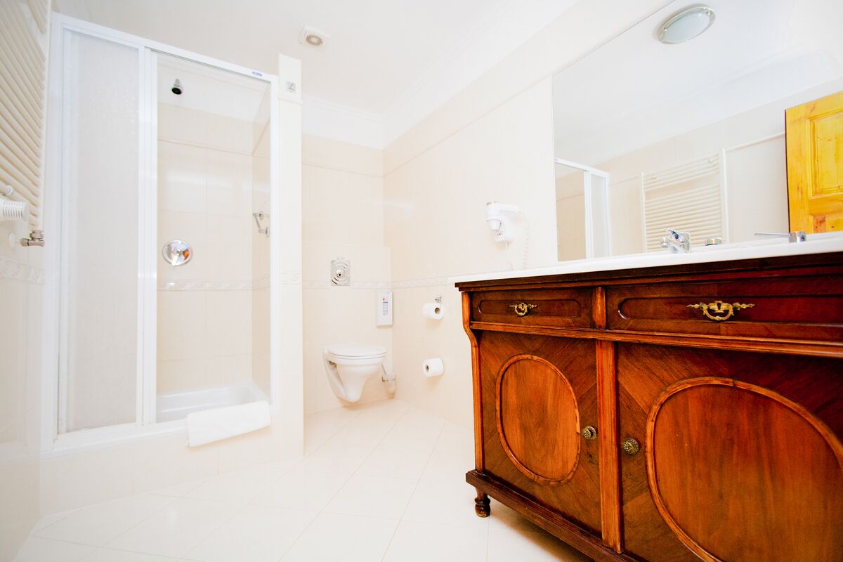 A bathroom with a shower, toilet, vanity with drawers, and a mirror.