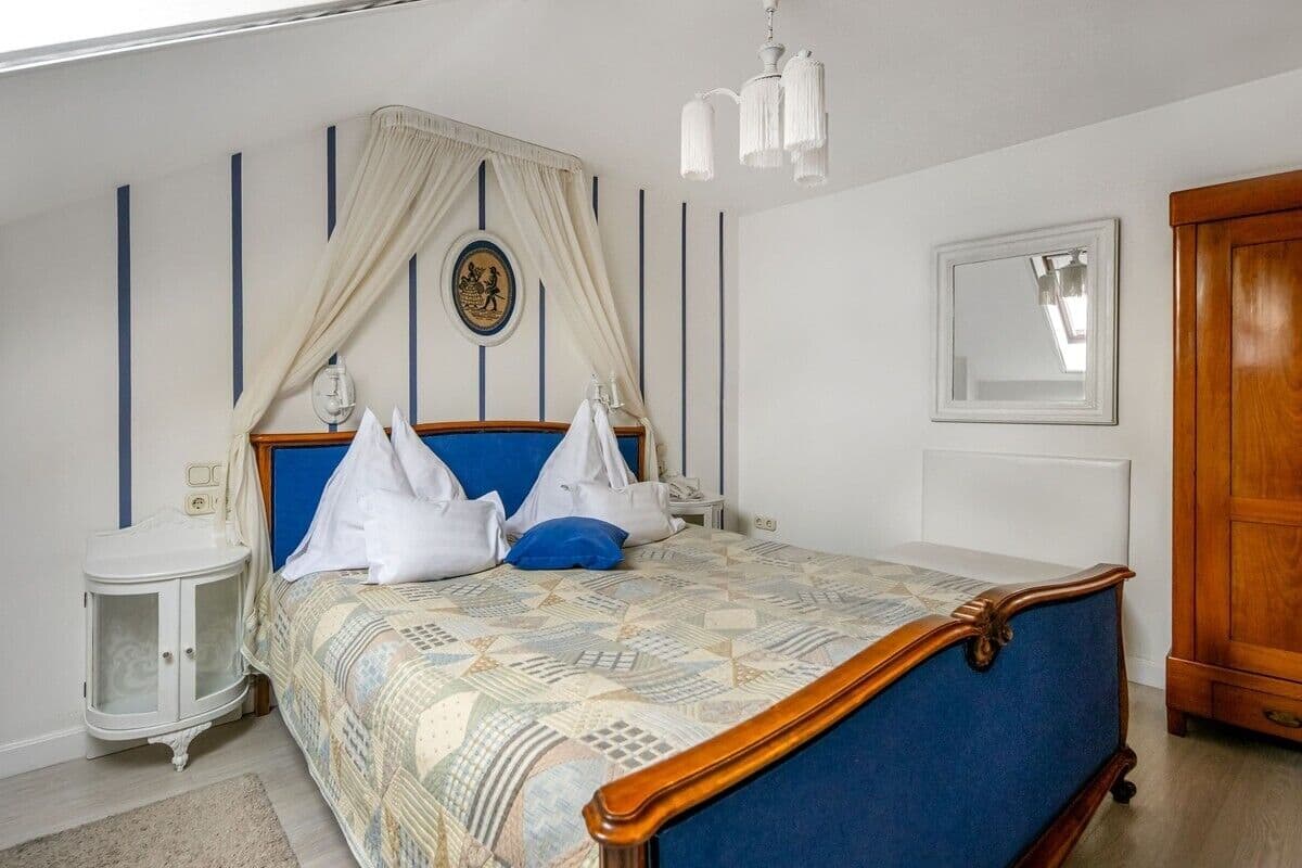 Ein Schlafzimmer mit Bett, Nachttischen, einem Kleiderschrank und einem Spiegel.