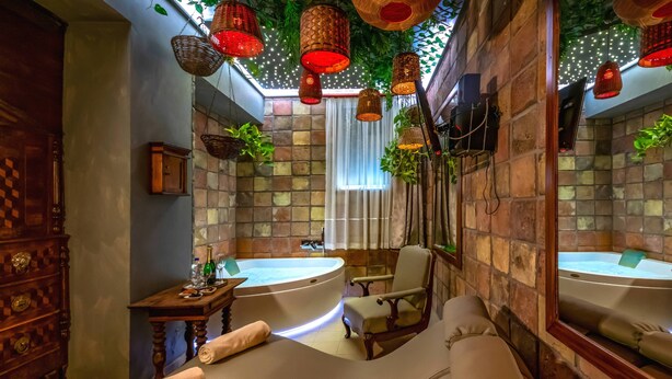 Un cuarto de spa con una bañera grande, una camilla de masaje y faroles rojos colgantes.