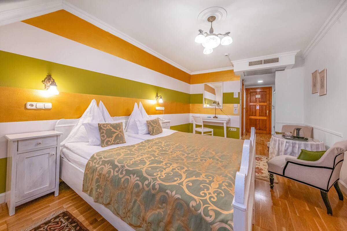 Ein Hotelzimmer mit Bett, Nachttischen, Schreibtisch, Stuhl und Spiegel.