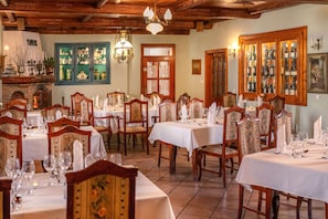 A dining area with multiple tables, chairs, and a wine display cabinet.
