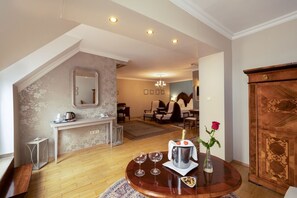 A modern living room with a wooden coffee table, a dining area with chairs, a kitchen with a counter, and a large wooden cabinet. - Hotel Szárcsa (Szekesfehervar)