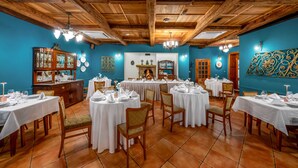 Un comedor con mesas redondas, sillas y una chimenea.