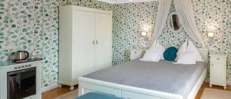 Un dormitorio con cama, armario, mesita de noche, lámpara y televisor.