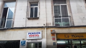 Un edificio con un letrero que dice 'Pension Hostel', un letrero que dice 'La Monyos' y un letrero de estacionamiento con la letra 'P'.