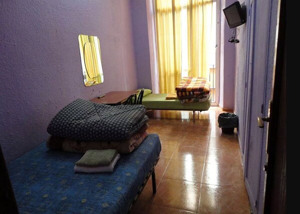 A small room with a bed, a chair, a table, and a television on the wall. - Central Station Hostel Barcelona (Barcelona)