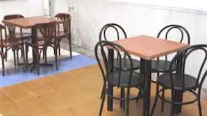Una habitación con alfombra azul, mesas de madera y sillas negras.