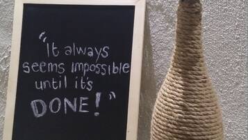 Ein gerahmter Spruch an einer Schiefertafel neben einer gewebten Vase mit einer Pflanze.