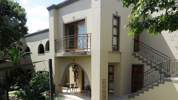 Un bâtiment à deux étages doté d’un balcon, d’un escalier et d’un espace jardin.
