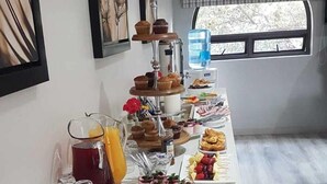 Un buffet de petit-déjeuner comprenant des croissants, des viennoiseries, des fruits et des boissons.