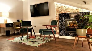 A modern living room with a fireplace, a flat-screen TV, and comfortable seating. - SleepWell Apartments Nowy Świat (Warsaw)