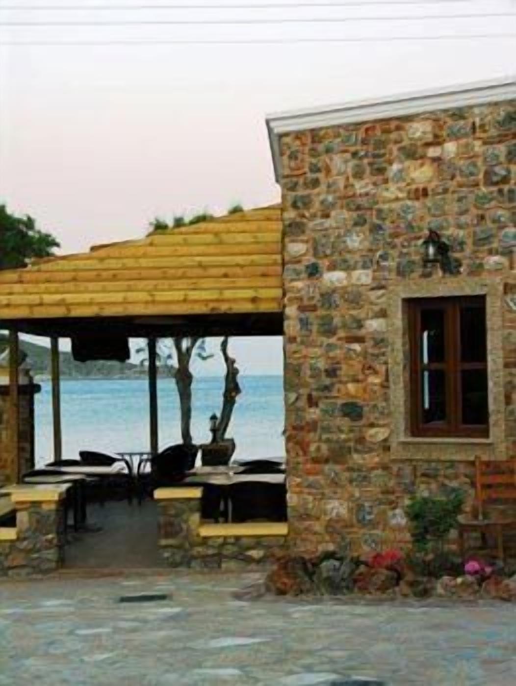 Un bâtiment en pierre doté d’une fenêtre et d’une pergola en bois surplombant une étendue d’eau.