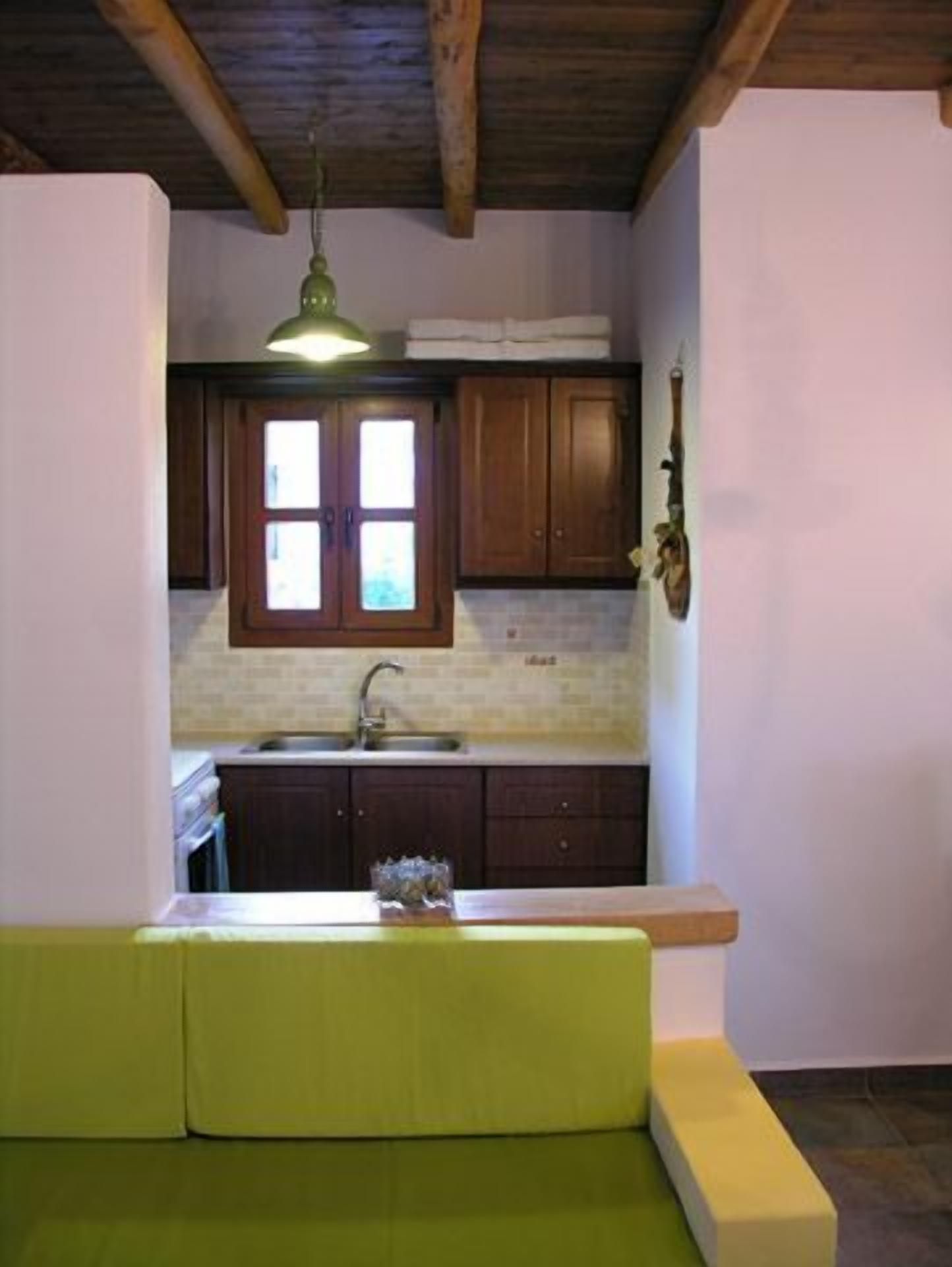 A kitchen with wooden cabinets, a built-in sink, and a green bench.