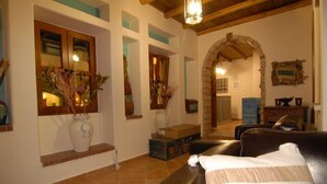 Uma sala de estar acolhedora com um sofá de couro, uma mesa de centro de madeira e uma janela grande com plantas decorativas.