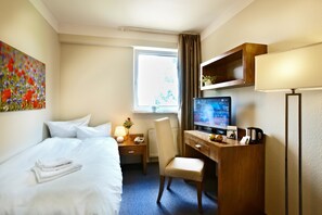 A hotel room with a bed, desk, chair, television, and a window with curtains. - Hotel Königstein Kiel by Tulip Inn (Kronshagen)