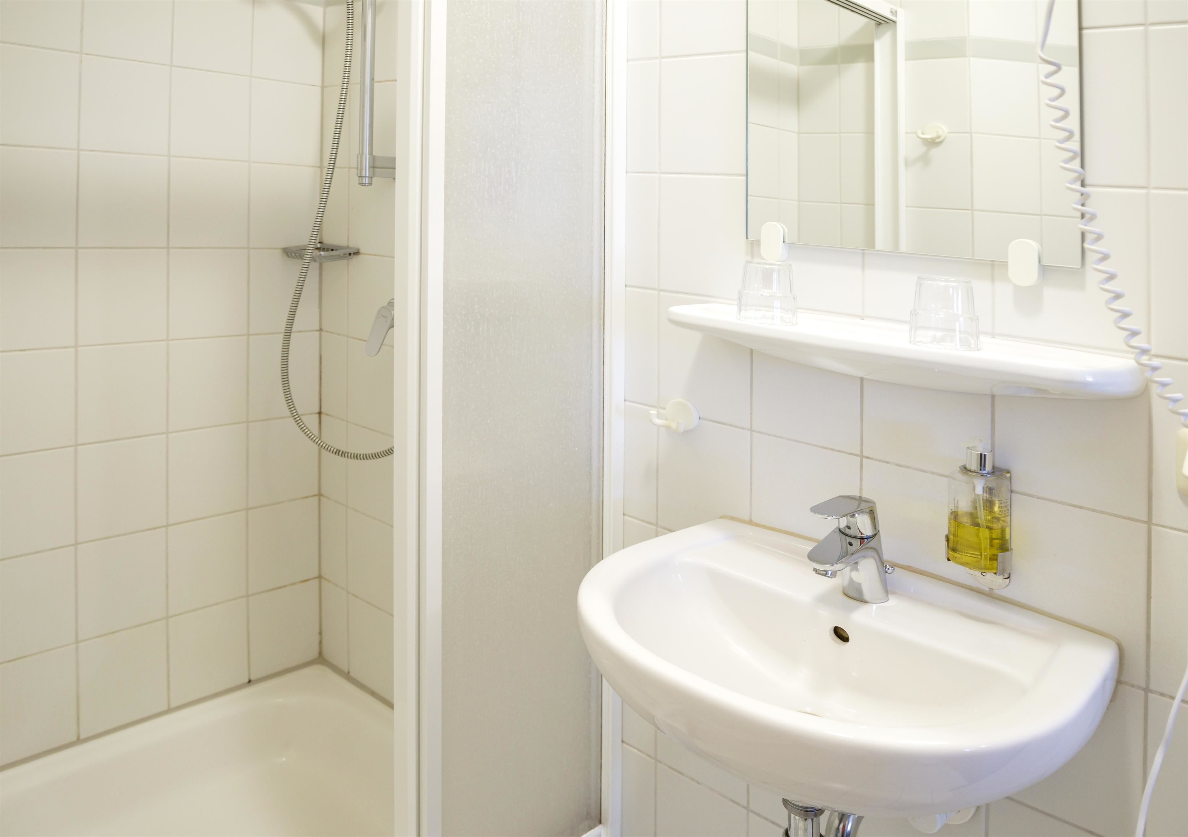 Ein Badezimmer mit Dusche, Waschbecken und Spiegel.